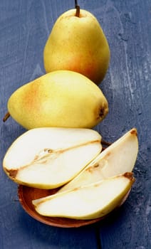 Arrangement of Full Body and Halves of Fresh Ripe Sweet Yellow Pears isolated on Dark Blue Wooden background 