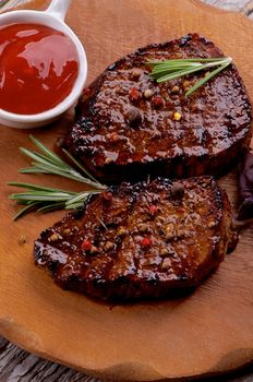 Delicious Roasted Beef Steaks with Spices and Tomato Sauce closeup on Wooden Plate 