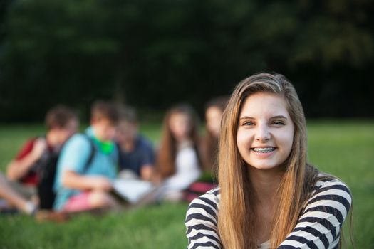 Cute smiling teenage girl with braces sitting outdoors