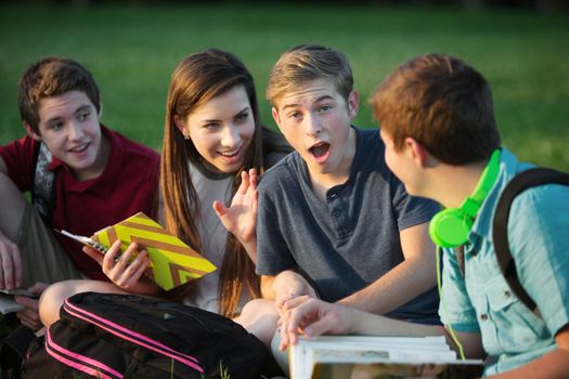 Surprised male student gossiping with friends outdoors