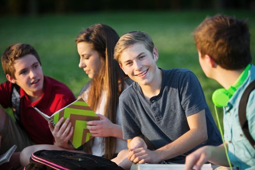Smiling confident male teenager with friends outdoors