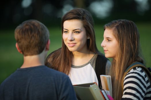 Group of three young Caucasian students talking outdoors