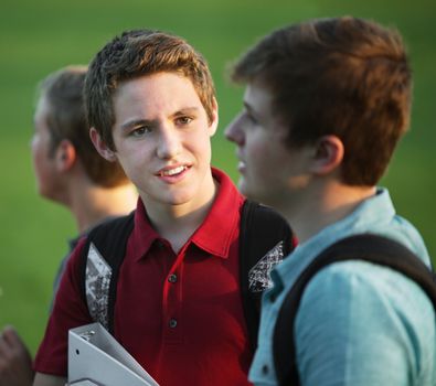 Two teen white male students talking outdoors