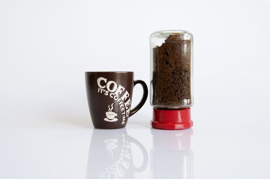 A black coffee storage tin next to a black and white mug