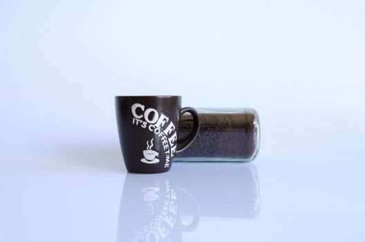 A black coffee storage tin next to a black and white mug