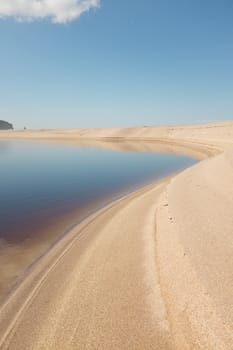 Steep white sand curves around the fresh water lagoon at The Sandwood bay beach, Sutherland, Scotland, UK.