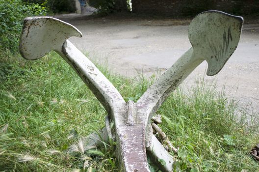 Big and ancient anchor exposed upon a meadow