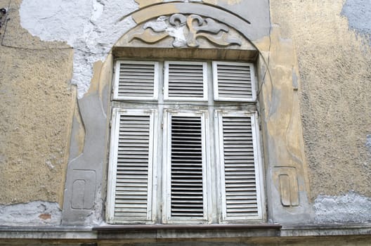 Old rotting wooden window on the crumbling wall in Bulgarian style