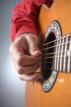 closeup of hands of a musician playing acoustic guitar