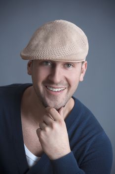 studio portrait of a young handsome man with cap, smiling