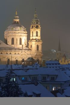 prague - view of snowy rooftops and st. nicolaus church in winter