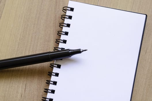 White notepad and ink pen on the wooden desk