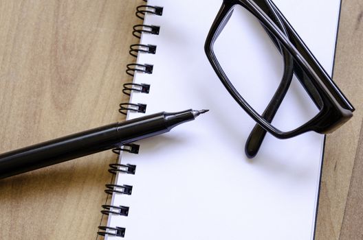 White notepad,glasses and ink pen on the wooden desk