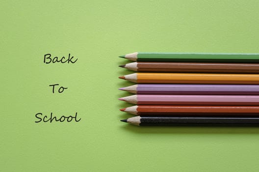 Colorful pencil crayons on a green background, back to school