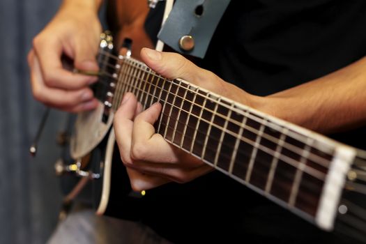 close up shot of a man with his fingers on the frets of a guitar playing