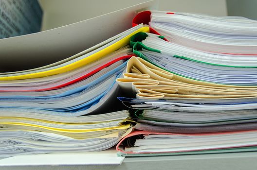 Red, green, blue and yellow office folders with boxes on the gray shelf