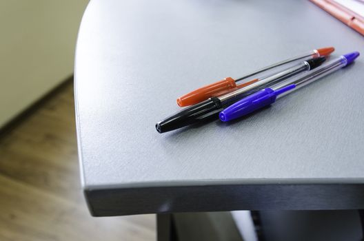 Three multicolor felt pens on wooden desk