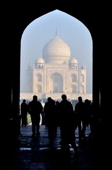 Picturesque view of people standing under an arch looking at Taj Mahal