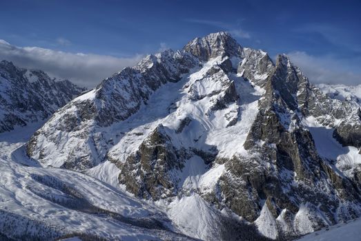 Close-up view of a high mountain covered in snow illuminated by the setting sun