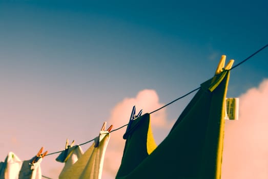 Close-up view of clothes on a clothesline held with clothes pegs at sunset              