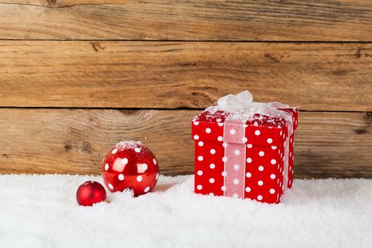 christmas red gift with snow, on wooden background