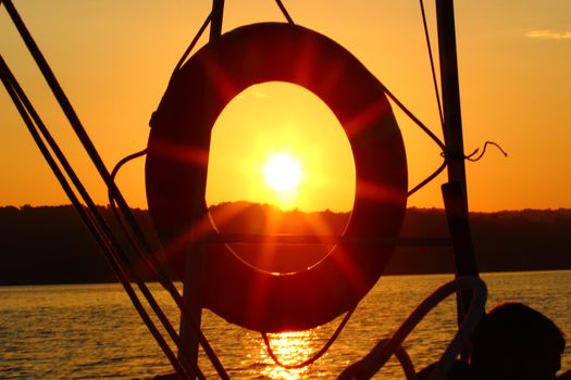 Sunset over the ocean and lifebuoy on the yacht