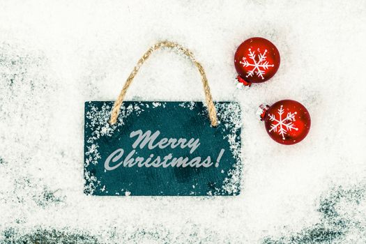 Black board of slate on rustic wooden background with snow