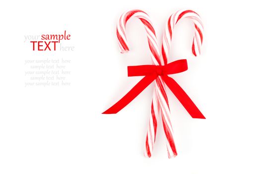 Close up of two candy canes tied with ribbon bow on white background