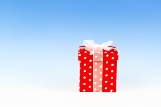 red gift box, polka dots with bow on blue background