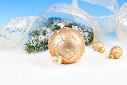 Christmas balls with ribbon on snow, on blue background