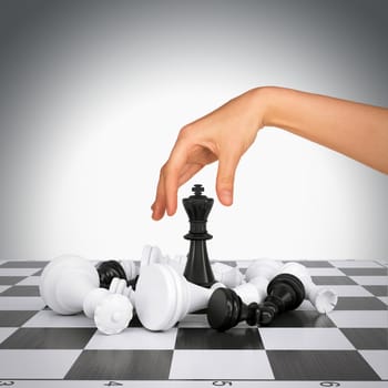 Woman hand touching king figure on chess board. Gray background. Business concept