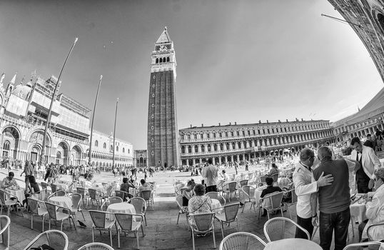 VENICE - APRIL 7, 2014: Tourists enjoy Saint Mark Square on a beautiful spring day. Venice is visted by more than 20 million people every year.