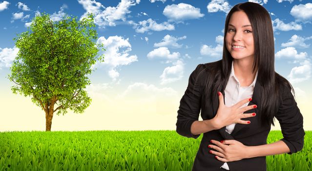Businesswoman in suit smiling and looking at camera. Tree and green landscape as backdrop