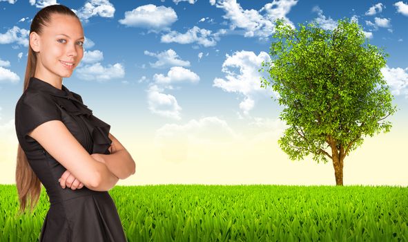 Businesswoman smiling and standing with crossed arms. Nature landscape with green grass, tree and sky as backdrop