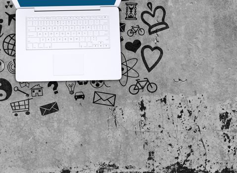 Laptop on concrete floor with various social icons. Computer concept