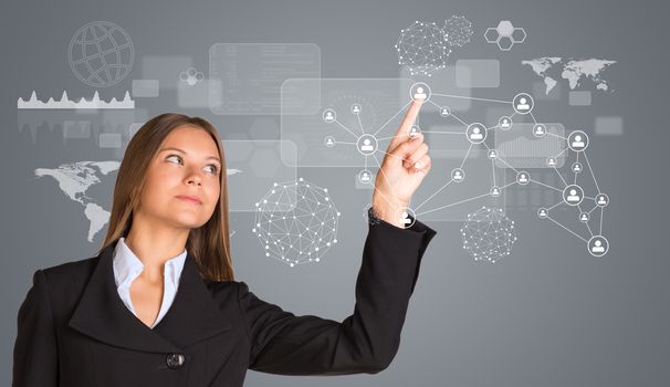 Beautiful businesswoman in suit pointing finger on network with people icons. World map and graphs in background