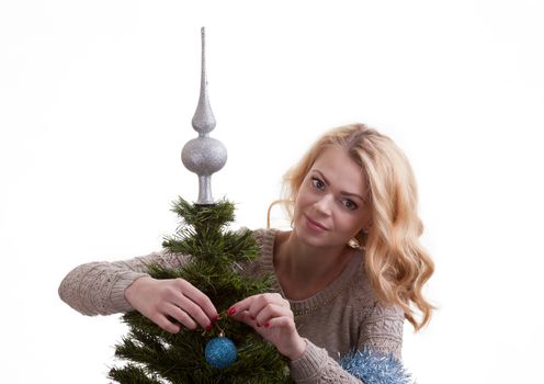 Beautiful young blonde girl decorates the Christmas tree