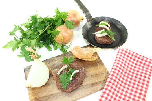 Ostrich steak with parsley on a light background