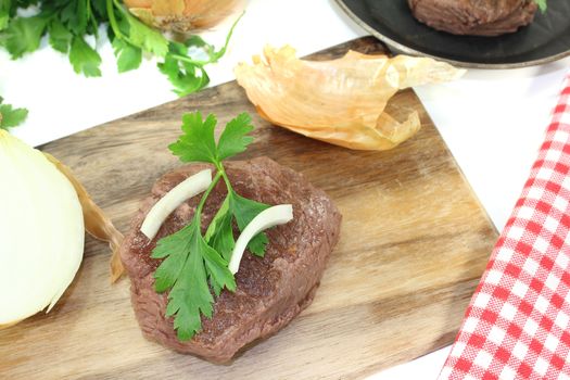 Ostrich steaks with sharp onions on a light background