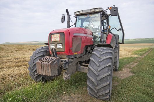 Red agriculture tractor on a field in summer