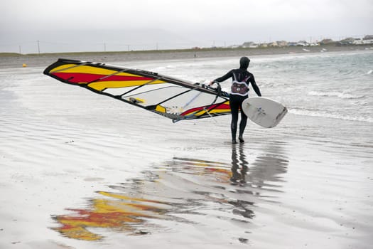 lone windsurfer getting ready to surf on the beach in the maharees county kerry ireland