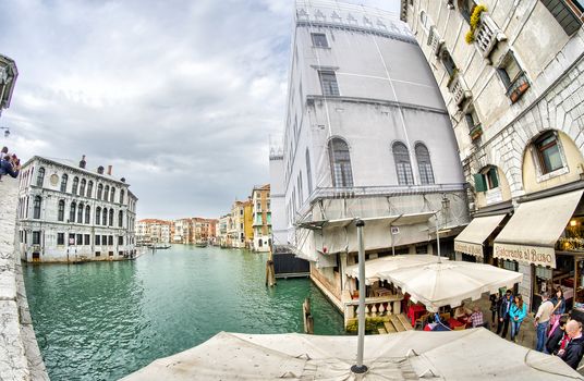VENICE - APRIL 7, 2014: Tourists enjoy city canals on a beautiful spring day. Venice is visted by more than 20 million people every year.