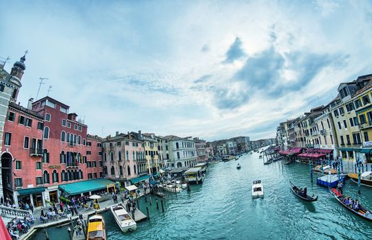 VENICE - APRIL 7, 2014: Tourists enjoy city canals on a beautiful spring day. Venice is visted by more than 20 million people every year.