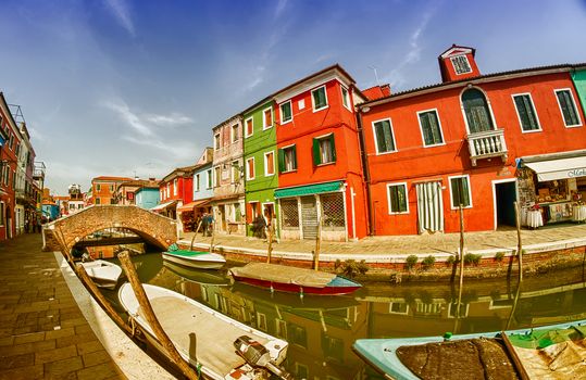 BURANO, ITALY - APRIL 8, 2014: Tourists enjoy colourful city buildings on a beautiful spring day. Island Burano village colors attract one million tourists annually.