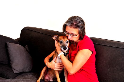 A Woman cuddling with dog on a grey sofa