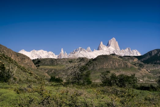 Panoramic view of snowy mountains rising above grassy hills in Los Glaciares National Park