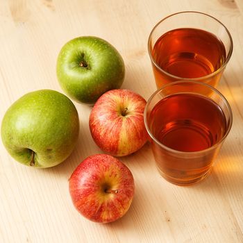 Glass of apple juice with apples on the table