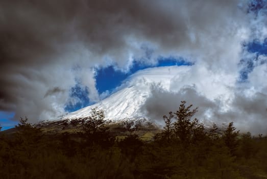 Breathtaking view of grey clouds rolling over mountain peak in Parque Nacional Vicente Perez Rosales                