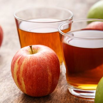 Glass of apple juice with apples on the table