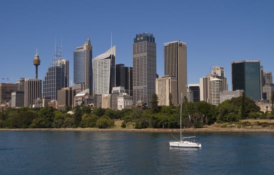 SYDNEY, AUSTRALIA - CIRCA DECEMBER 2009: View from over the bay onto downtown skyline with a lone white yacht in the foreground.